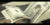 Animated contact sheet of four frames showing a stack of US dollar bills in various states of motion and orientation against a gray background.