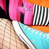 A close-up of a character's lower body wearing a pink striped top, black and white striped sleeves, fishnet stockings, and a light blue shoe with white laces.