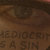 Pixelated brown-toned static image with indistinct text at the bottom and blurred shapes above.