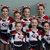 Group of cheerleaders in red, white, and black uniforms posing together with a large blue and red #1 graphic overlay.