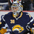Pixelated image of a hockey player in dark blue jersey with yellow accents, wearing goalie mask and gloves, against solid blue background with pixelated text.