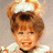 Pixelated image of a child with brown hair in a high ponytail, wearing white clothing against a pink background with text.
