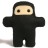 Pixelated figure in black hooded outfit with light skin face, brown eyes, and outstretched arms against white background.