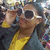 Animated icon of a person with dark hair wearing white sunglasses and yellow-and-gray clothing, holding hands near the face.