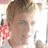 Pixelated close-up of a person with light brown hair, wearing a white shirt and red floral accessory on the left side.