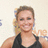 A person in a black sleeveless top smiles against a light background with partial orange and blue text.