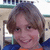 Pixelated static image of a person with short brown hair wearing blue and orange clothing against an indistinct background.