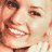Pixelated close-up of a smiling person's face with visible eyes, nose, mouth, and hair in warm tones.