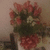 A bouquet of pink flowers with green foliage and white accents in a red-patterned vase against a light background.