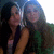Two women pose closely together in a pixelated image with one woman in a dark top and the other in a green top, both with long hair.