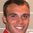A pixelated image of a smiling person with short dark hair, wearing a red garment, next to orange and gray text blocks.