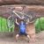 Pixelated static image of a figure with blue torso and white limbs against green and brown background