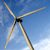 A wind turbine with three blades against a blue sky background, rendered in pixelated style with light brown blades and a dark central hub.