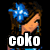 Pixelated character with brown hair and blue outfit, wearing a flower accessory, standing against black background with text overlays.