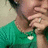 A person in a green shirt with a white heart-shaped pendant rests their chin on one hand, showing slight variations