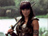 Pixelated image of a person with long dark hair and bangs wearing a sleeveless top, holding an object near their chest against a blurred background.