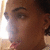 Pixelated close-up of a person's face with brown skin tone, dark hair, and visible ear showing light-colored earring.