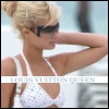 A woman with blonde hair in a bun wears dark sunglasses and a white bikini top with small colorful patterns, her right arm raised near her head.