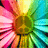 A vibrant, pixelated flower with radiating petals in pink, yellow, green, and cyan hues, centered on a brown core, displayed in a four