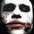 A split-screen image showing a white-faced character with dark eyes and mouth, flames on the chest, and text reading 'WHY SO SERIOUS' against a blue background.