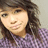 Pixelated static image of a person with dark brown hair and light skin wearing a purple checkered shirt against a neutral background.