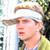 Pixelated static image of a person wearing a white headband and dark cap, with visible facial features including eyes, nose, mouth, and ear, set against an indistinct background.