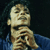 Static pixelated image of a person in blue clothing with hands clasped near the face against dark background.