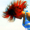 A person with red hair in motion, wearing a blue and white striped sleeveless top, viewed from the side against a light background.