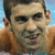 Pixelated close-up of a person with short dark hair, light skin, and visible facial features including eyes, nose, mouth, and ears against a blue background.