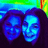 Two stylized faces with blue and purple tones against a dark background, featuring a gradient sky-like top section with green, blue, and yellow hues.