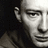 Black-and-white pixelated portrait of a person with short hair on left, yellow text blocks on right and bottom against black background.