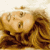 Pixelated static image of a cartoonish figure with brown hair and light skin, wearing dark clothing against a beige background with blurred shapes.
