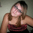 Pixelated image of a person with long brown hair wearing a dark red strapless top against a muted gray background.