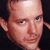 Pixelated close-up of a person's face with visible facial features and partial ear, set against dark background in static 50x50 icon format.