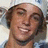 A static image with a pixelated portrait of a person wearing a white head covering and light-colored clothing, alongside green text on black background.