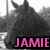 Pixelated grayscale image of a dark, indistinct figure with two horn-like protrusions, overlaid with bright pink text reading JAMIE on a black background.