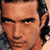 Pixelated close-up of a man's face with dark hair and light skin, rendered in warm brown tones on a neutral background.