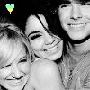 Black-and-white photo of three people smiling closely together with a small green and yellow heart icon in the top-left corner.