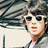 Pixelated image of a person with dark hair wearing white sunglasses, red lips, and a light-colored top against a blurred background.