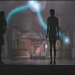 Pixelated static image of a dark silhouette figure standing against a blurred background with colorful light streaks and abstract shapes.