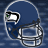 Blue football helmet with white and green logo, silver face mask, on blue patterned background.