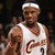 Pixelated image of a person wearing a white sleeveless jersey with red and black markings, a white headband, and a dark background.