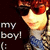 Pixelated image of a character with red hair and sunglasses, wearing a white shirt and blue jeans, standing against dark background with text 'my boy!' on left.