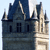 Pixelated view of a stone building with dark blue roof, multiple windows, and light-colored tower under light blue sky.