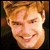 Pixelated close-up of a smiling person with light brown hair against dark background, rendered in low-resolution 256x256 pixels.