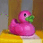Pixelated pink rubber duck with green mouthpiece sits on yellow and white surface against brown background, surrounded by bright magenta text