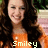 A pixelated image of a person with long dark hair wearing an orange top, with text below the figure.