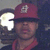 A pixelated image shows a person wearing a maroon baseball cap with a white 'W' logo, standing against a dark background with a bright circular light source on the left.