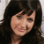 Pixelated close-up of a person with dark hair and bangs, wearing a dark top against a light background.