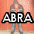 A person in a brown jacket and red shirt stands against an orange brick wall with text overlays changing across frames.